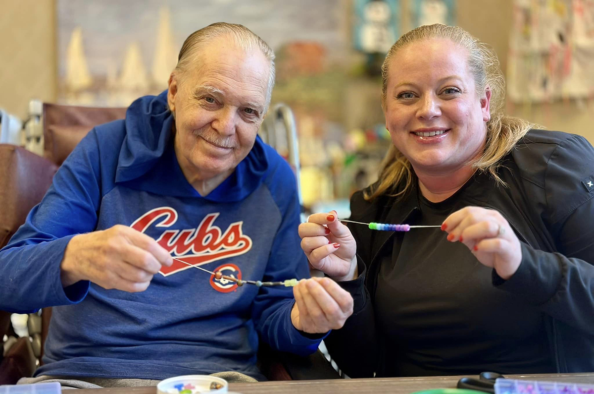 Churchill Place resident and staff member making friendship bracelets