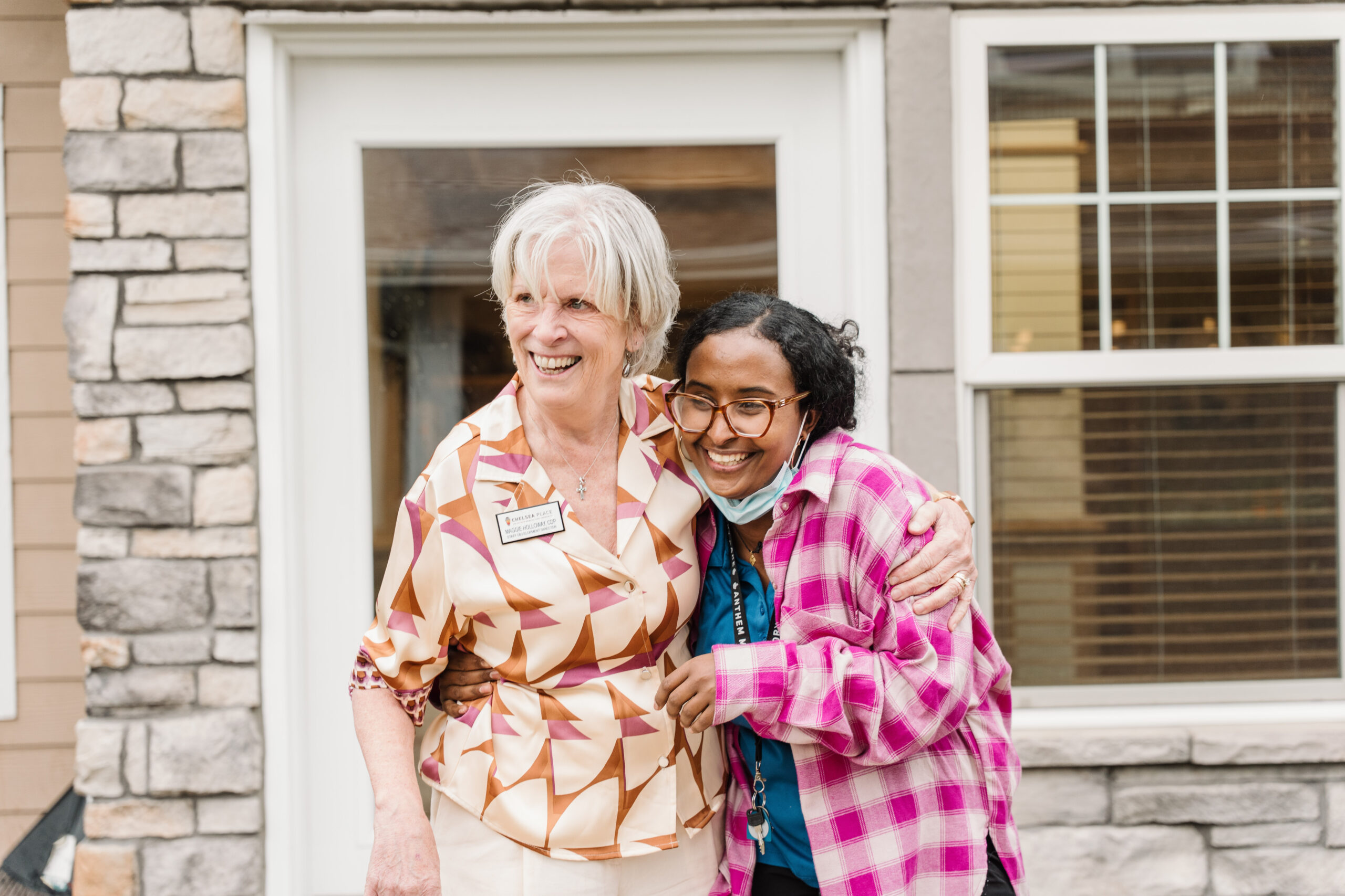 Two staff members smiling and hugging outside