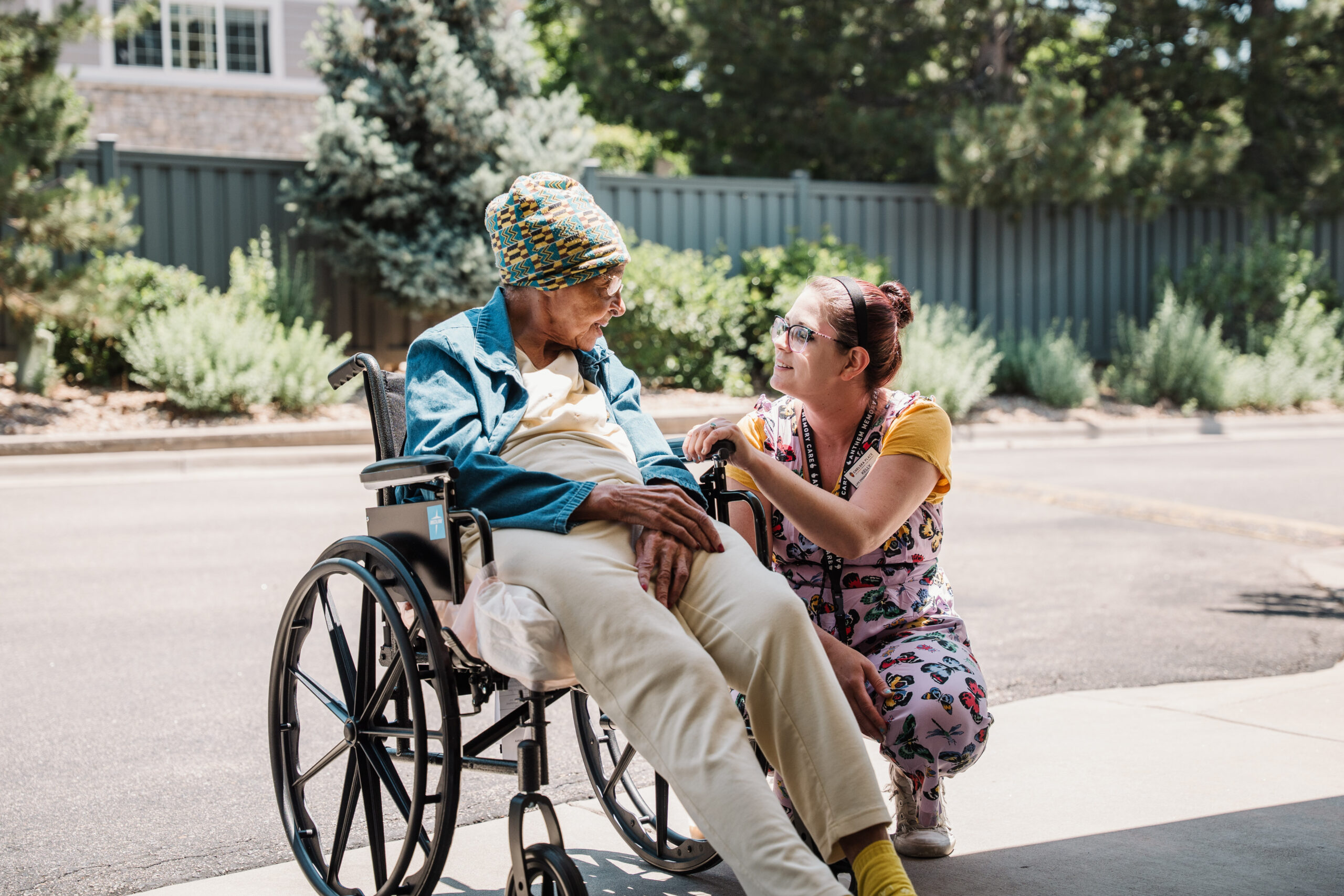 Chelsea Place staff member talking to a resident in a wheelchair outside